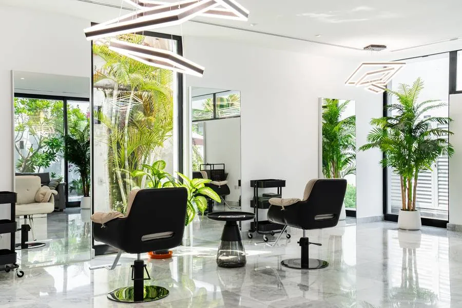 Styling floor at Vereya Hair Dubai: black chairs, full-height mirrors and daylight through glazing onto planting